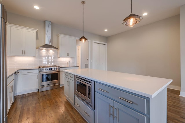 kitchen with stainless steel appliances, a kitchen island, white cabinets, and wall chimney exhaust hood