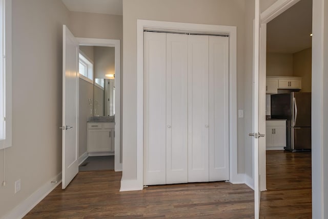 unfurnished bedroom with dark hardwood / wood-style floors, stainless steel refrigerator, and a closet