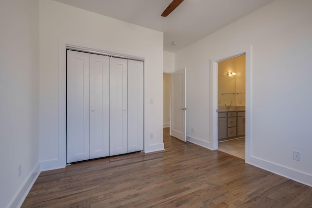 unfurnished bedroom with dark hardwood / wood-style floors, connected bathroom, ceiling fan, and a closet