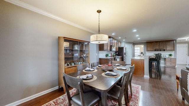 dining area with dark wood-type flooring and crown molding