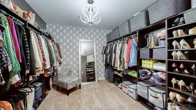 spacious closet with light colored carpet and an inviting chandelier