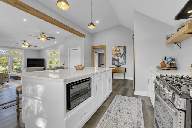 kitchen featuring vaulted ceiling, stainless steel gas stove, white cabinets, hanging light fixtures, and a center island