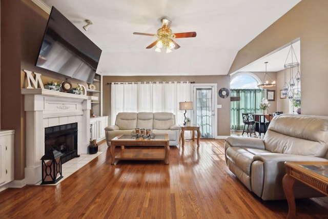 living room with a fireplace, lofted ceiling, light hardwood / wood-style flooring, ceiling fan, and built in shelves