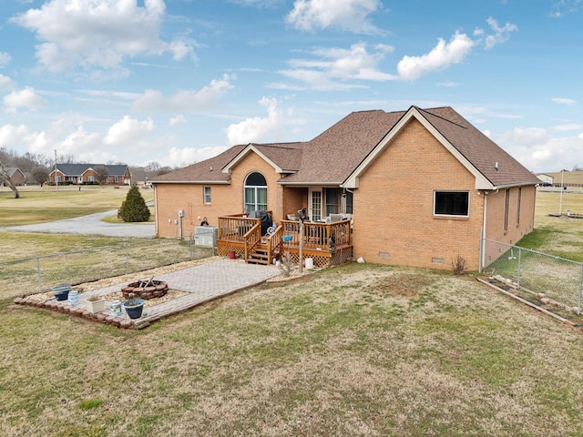 back of property with a wooden deck, a fire pit, and a lawn