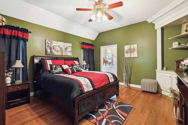 bedroom with hardwood / wood-style flooring, ceiling fan, vaulted ceiling, and ensuite bath