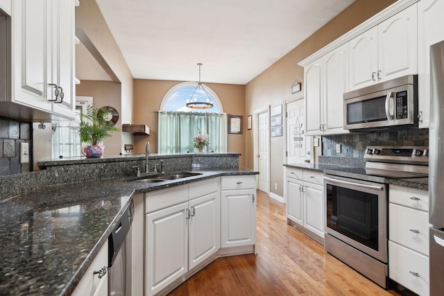 kitchen with hanging light fixtures, white cabinetry, appliances with stainless steel finishes, and sink