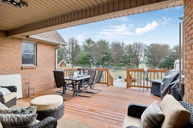 wooden terrace with an outdoor living space and grilling area