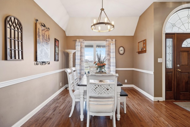 dining room with vaulted ceiling, dark hardwood / wood-style floors, and an inviting chandelier