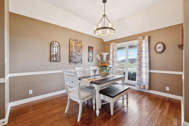 dining area featuring hardwood / wood-style flooring, lofted ceiling, and an inviting chandelier