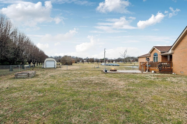 view of yard featuring an outbuilding, a wooden deck, a fire pit, and a garage