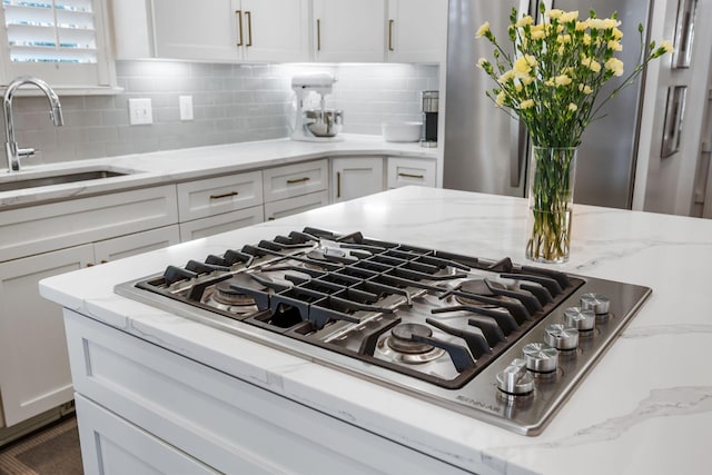 details with stainless steel appliances, white cabinetry, light stone countertops, and sink