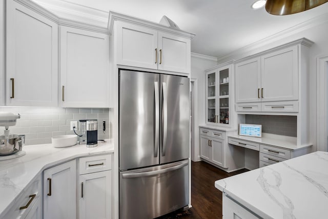 kitchen featuring backsplash, stainless steel fridge, light stone countertops, and white cabinets