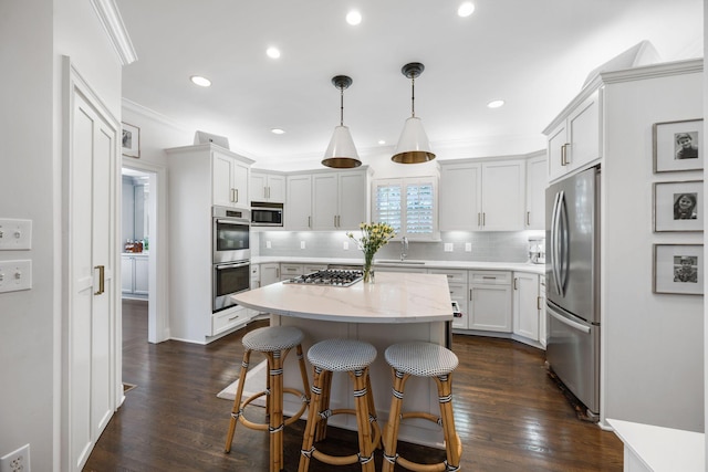 kitchen with white cabinetry, decorative light fixtures, a kitchen island, stainless steel appliances, and light stone countertops