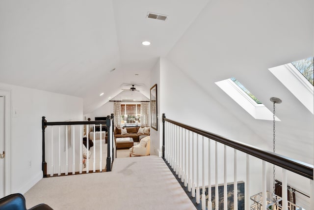 corridor featuring lofted ceiling with skylight and light carpet