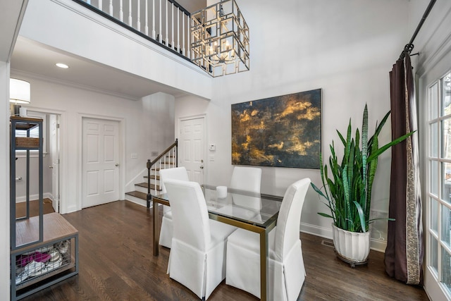 dining space featuring crown molding, dark hardwood / wood-style flooring, a chandelier, and a high ceiling