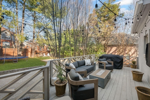 wooden deck featuring a yard, an outdoor hangout area, a trampoline, and grilling area