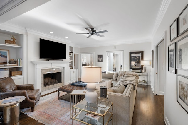 living room featuring crown molding, a fireplace, dark hardwood / wood-style flooring, and built in shelves