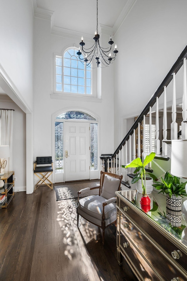 entrance foyer with crown molding, dark wood-type flooring, a notable chandelier, and a towering ceiling