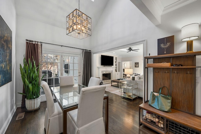 dining space with dark hardwood / wood-style floors, ornamental molding, a fireplace, and a high ceiling