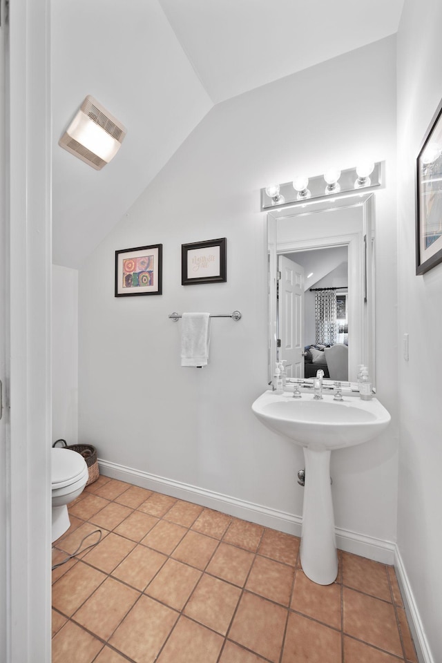 bathroom with sink, toilet, tile patterned flooring, and vaulted ceiling