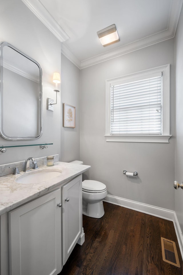 bathroom featuring vanity, hardwood / wood-style floors, ornamental molding, and toilet