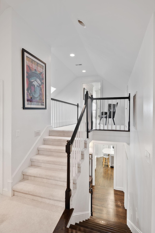 stairs with hardwood / wood-style flooring and vaulted ceiling