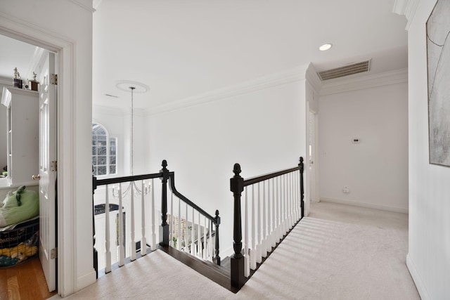 hallway featuring light carpet, ornamental molding, and a chandelier