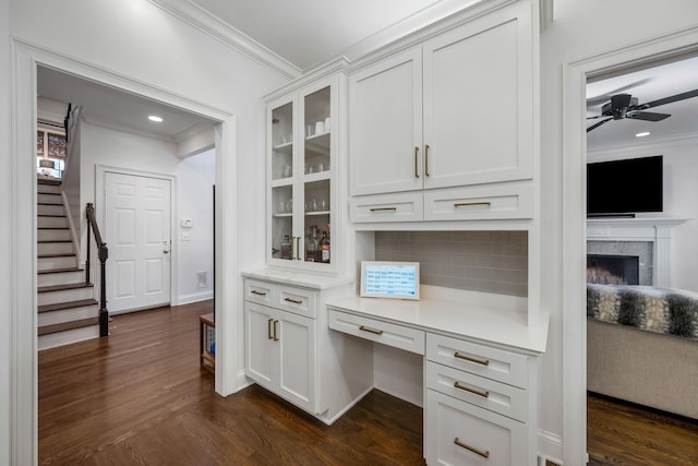 office space featuring ornamental molding, dark wood-type flooring, and built in desk