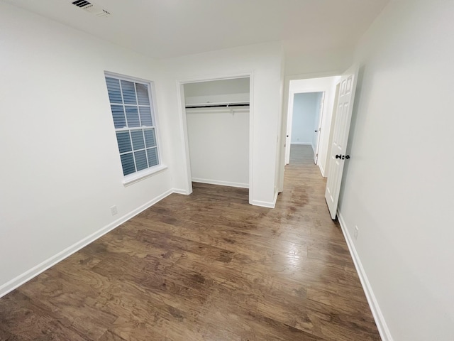 unfurnished bedroom featuring dark wood-type flooring and a closet