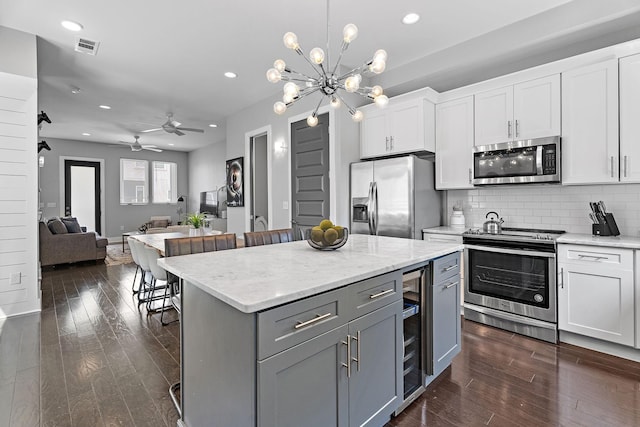 kitchen with white cabinetry, a kitchen island, stainless steel appliances, a kitchen bar, and decorative light fixtures