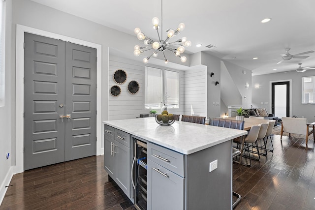 kitchen featuring gray cabinetry, hanging light fixtures, a center island, wine cooler, and a kitchen bar