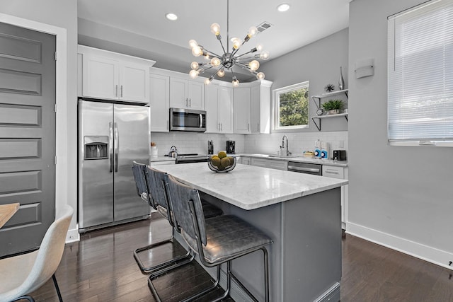 kitchen with a kitchen island, appliances with stainless steel finishes, pendant lighting, sink, and white cabinets