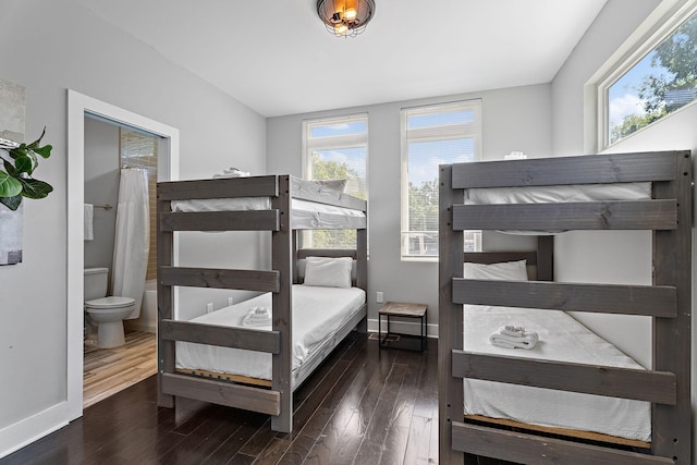 bedroom with connected bathroom and dark hardwood / wood-style floors