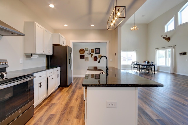 kitchen with pendant lighting, white cabinetry, stainless steel appliances, and a center island with sink