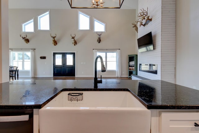 kitchen with sink, a high ceiling, and dark stone countertops