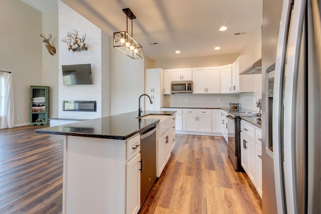 kitchen featuring white cabinetry, hanging light fixtures, light wood-type flooring, an island with sink, and stainless steel appliances