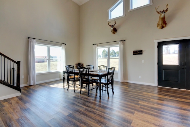 dining space with a wealth of natural light, dark wood-type flooring, and a high ceiling