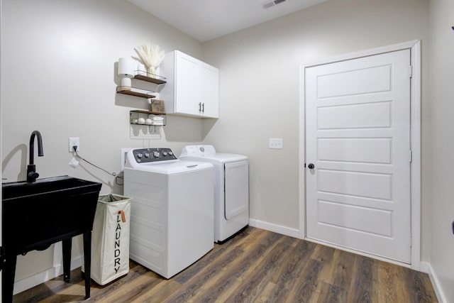 washroom with cabinets, washing machine and dryer, and dark wood-type flooring