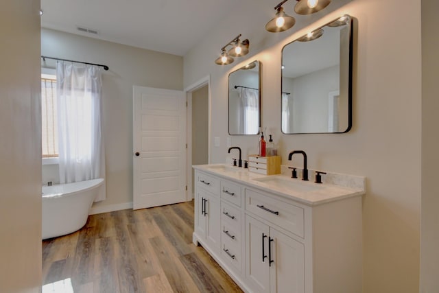 bathroom with wood-type flooring, a tub, and vanity