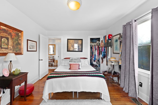 bedroom with a spacious closet, hardwood / wood-style floors, and a closet