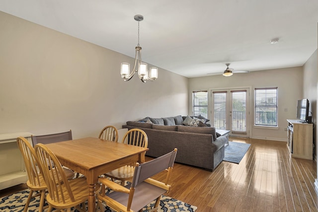 dining room with ceiling fan with notable chandelier and light hardwood / wood-style floors