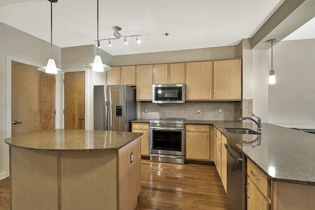 kitchen featuring sink, decorative light fixtures, dark stone countertops, appliances with stainless steel finishes, and decorative backsplash