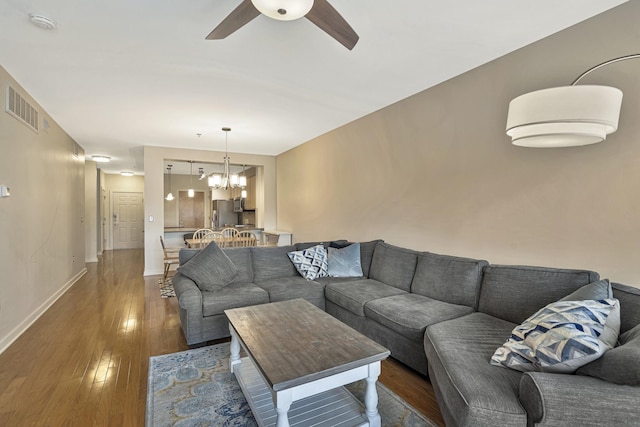 living room featuring ceiling fan with notable chandelier and dark hardwood / wood-style floors