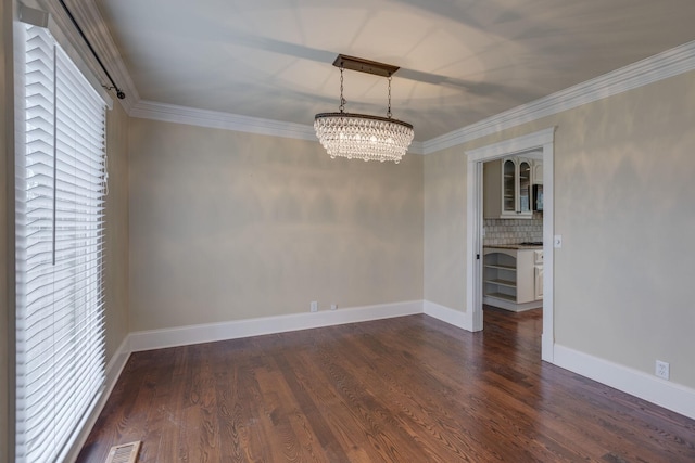 empty room with ornamental molding, dark hardwood / wood-style floors, and a notable chandelier