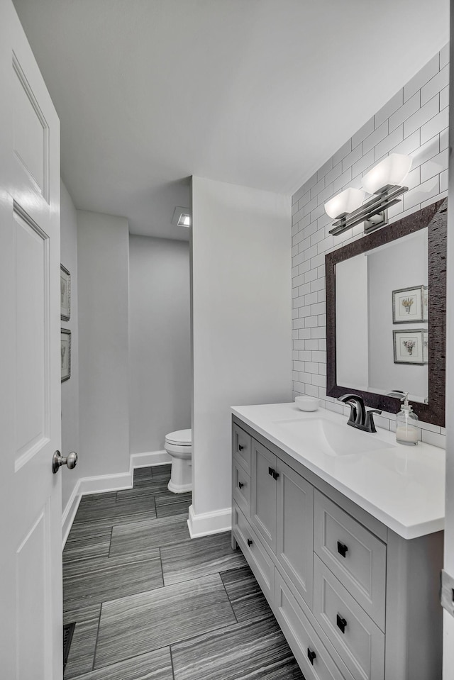 bathroom with vanity, toilet, and decorative backsplash