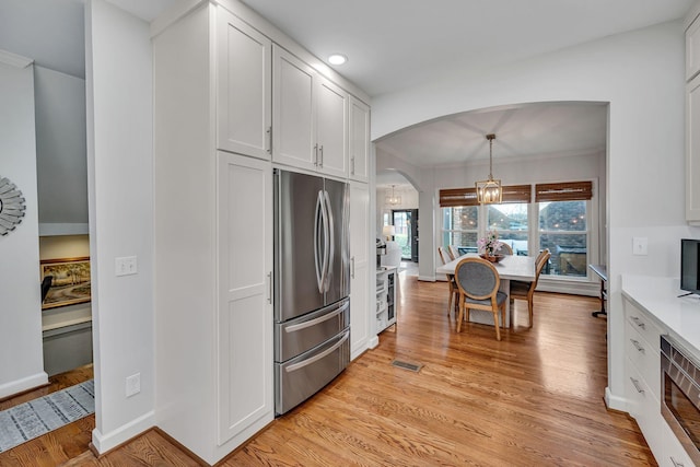 kitchen with white cabinetry, stainless steel fridge, hanging light fixtures, and light hardwood / wood-style flooring