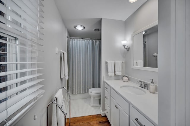 bathroom with walk in shower, vanity, toilet, and wood-type flooring