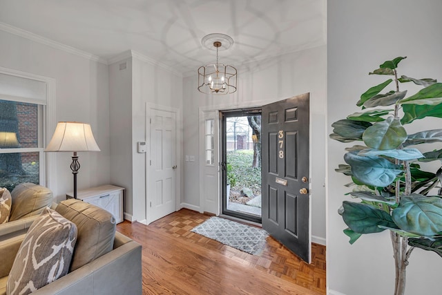 foyer entrance with crown molding, light parquet flooring, and a chandelier