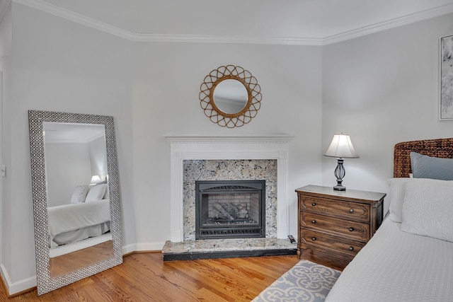 bedroom with crown molding, hardwood / wood-style floors, and a high end fireplace