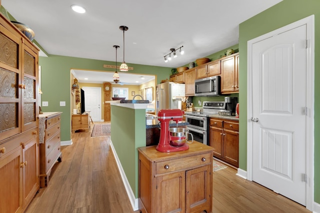 kitchen with stainless steel appliances, a kitchen island, light hardwood / wood-style floors, and hanging light fixtures